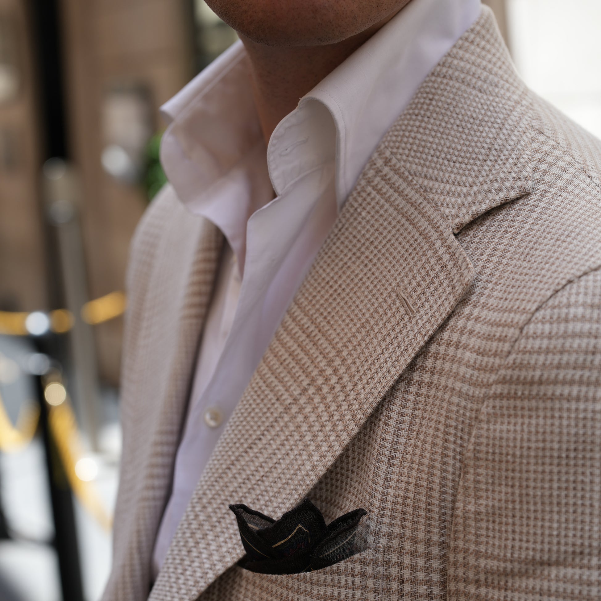 Closeup of tan plaid jacket with brown pocket square 