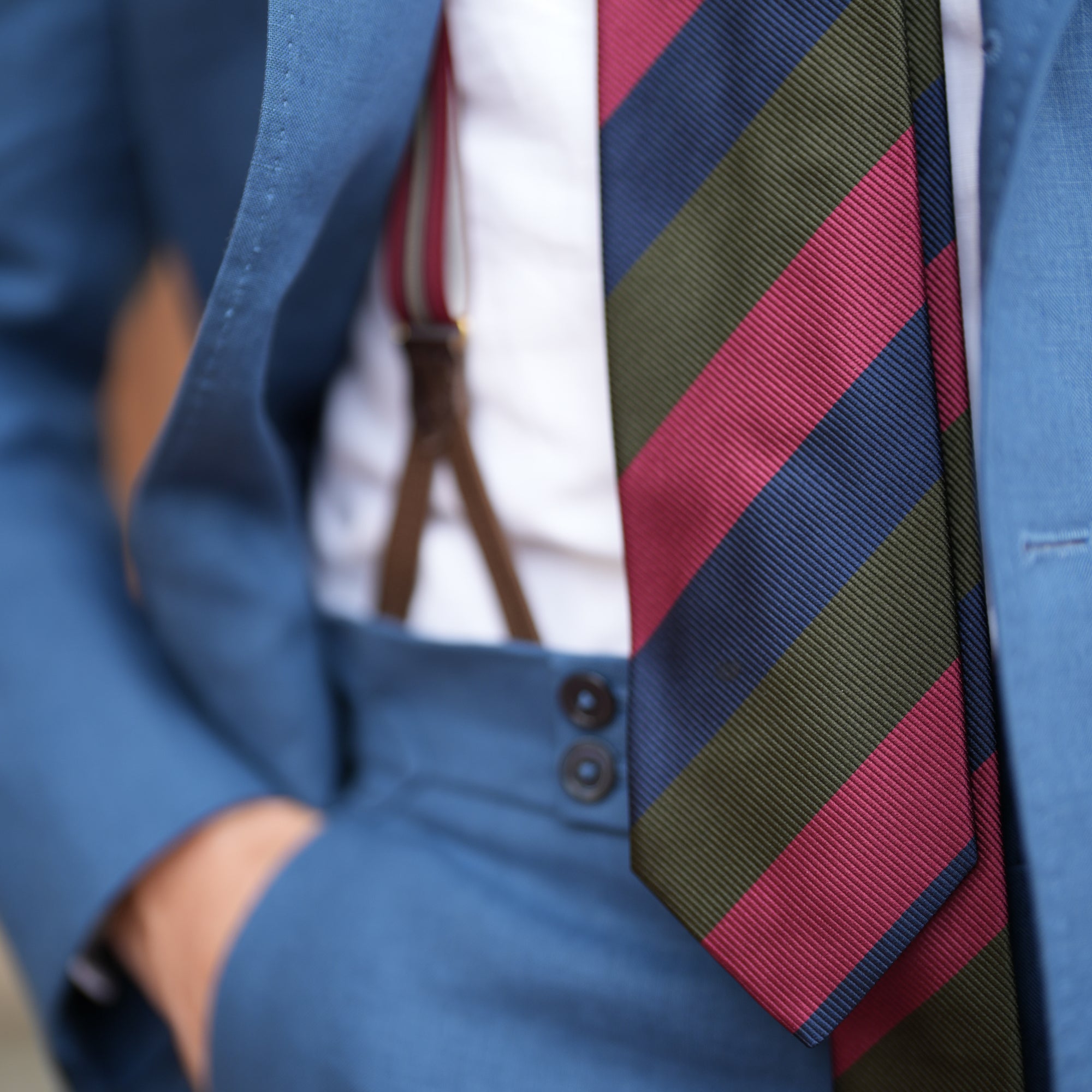 closeup of blue linen trouser details of waistband with striped tie
